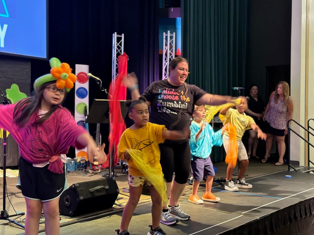 Miss Bri and children dancing energetically on stage during a Zumbini performance
