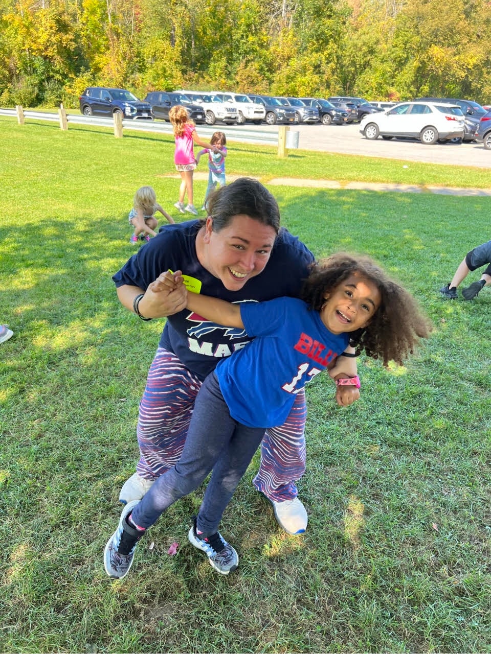 Miss Bri playing and dancing with a child at an outdoor event